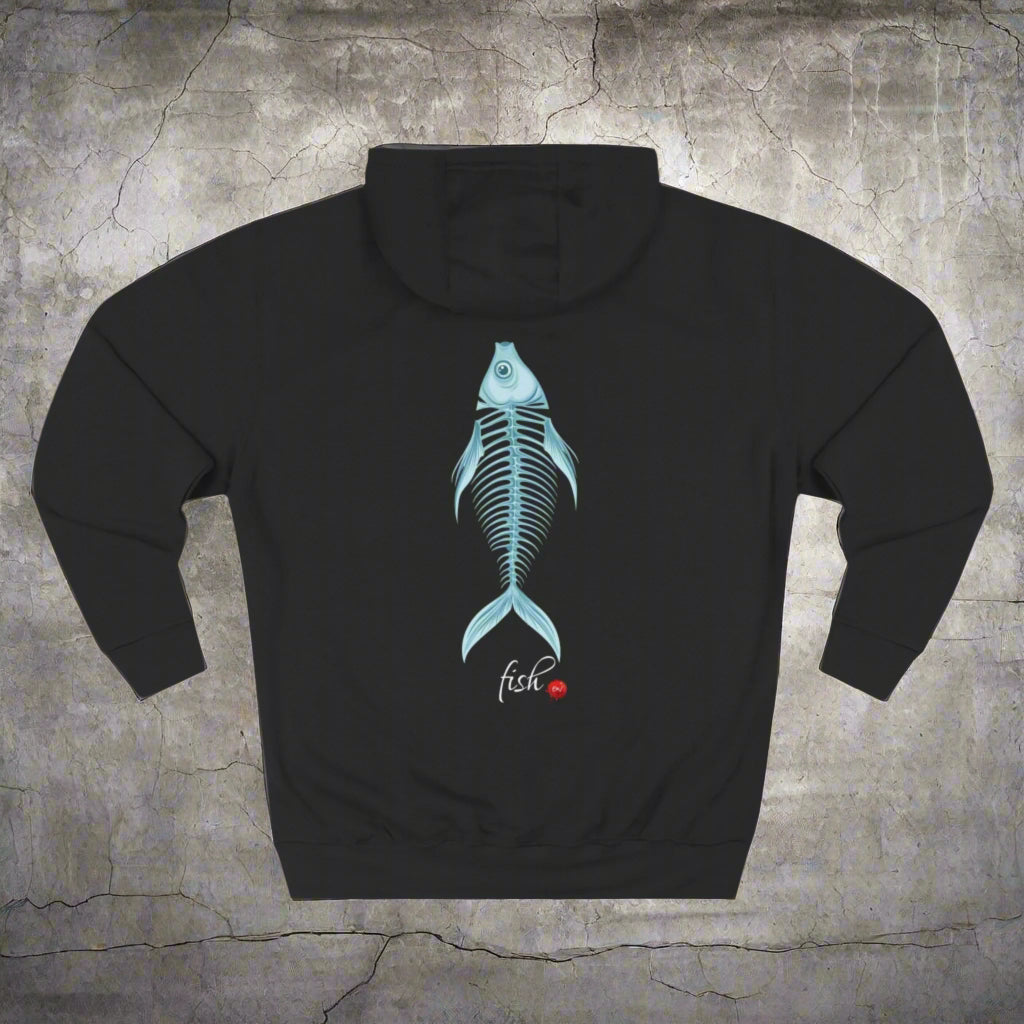 A person wearing a black fleece hoodie with a fish bone design on the back, standing against an orange background.